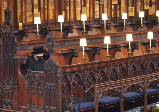 Ratu Elizabeth II terlihat duduk sendirian ketika prosesi pemakaman Pangeran Philip berlangsung di Kapel St George. Hal itu karena keluarga kerajaan sangat mematuhi peraturan COVID-19 Inggris. Aturan ini pun berlaku bagi 30 tamu lainnya yang hadir melayat Pangeran Philip. Foto: Dok. Associated Press