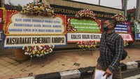 Warga melintas di depan karangan bunga bertuliskan dukungan terhadap aparat untuk mengusut tuntas kasus dugaan korupsi Dinas Damkar Depok, di Polrestro Depok, Depok, Jawa Barat, Senin (19/4/2021).