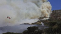 Proses pengendalian api juga menggunakan empat helikopter untuk melakukan pemadaman melalui udara (water bomb). AP Photo/Nardus Engelbrecht  