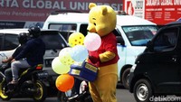 Seperti pria ini yang menjual balon dengan memakai kostum Winny The Pooh.