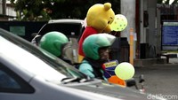 Ia menawarkan balon kepada para pengendara yang selesai mengisi bahan bakar.