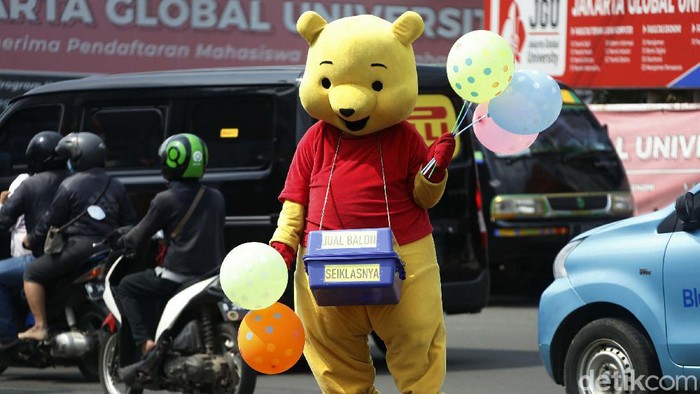 Seorang warga beraksi dengan kostum badut di depan SPBU Jakarta. Dia menjual balon dengan harga seikhlasnya.
