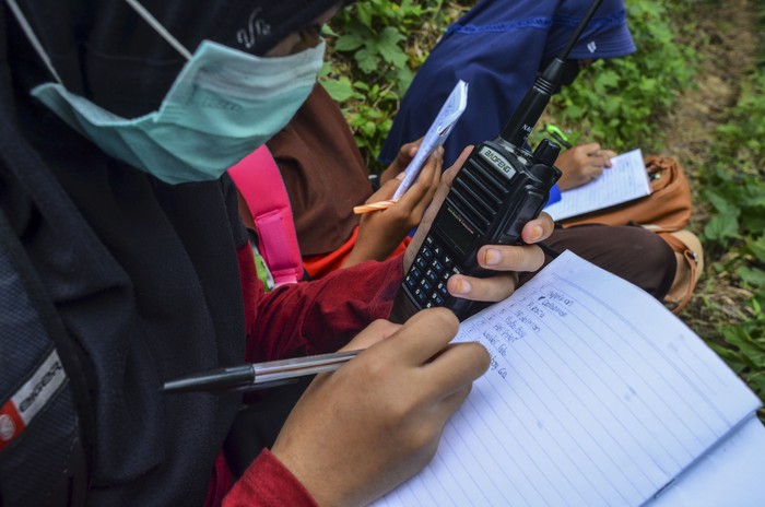 Siswa sekolah Madrasah Ibtidaiyah Pesawahan mendengarkan arahan wali kelas dari radio Handy Talky (HT) saat pembelajaran jarak jauh secara kelompok di Rumah Dusun Ciakar, Desa Pasawahan, Kecamatan Banjaranyar Kabupaten Ciamis, Jawa Barat.