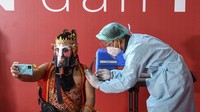 Seorang seniman dengan kostum pewayangan disuntik dosis pertama vaksin COVID-19 saat vaksinasi massal bagi seniman dan budayawan di Galeri Nasional, Jakarta.