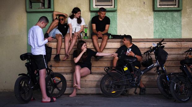 People without face masks watch the sunset, in Tel Aviv, Israel, Sunday, April 18, 2021. Israel has lifted a public mask mandate and fully reopened its education system in the latest easing of coronavirus restrictions following its mass vaccination drive. (AP Photo/Oded Balilty)