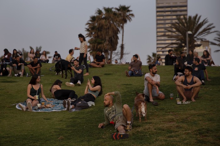 People without face masks watch the sunset, in Tel Aviv, Israel, Sunday, April 18, 2021. Israel has lifted a public mask mandate and fully reopened its education system in the latest easing of coronavirus restrictions following its mass vaccination drive. (AP Photo/Oded Balilty)
