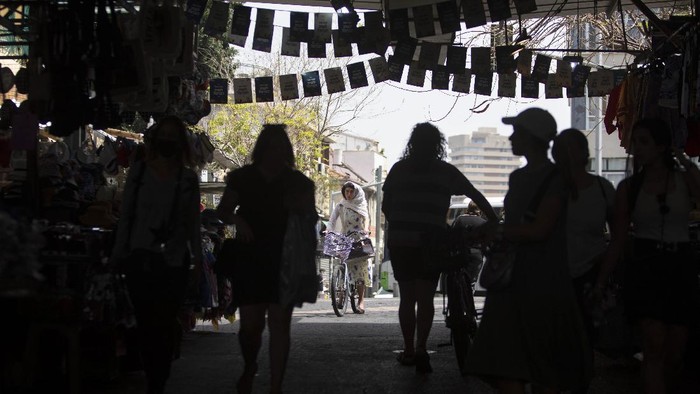Israelis walk in a market in Tel Aviv, Israel, Sunday, April 18, 2021. Israel has lifted a public mask mandate and fully reopened its education system in the latest easing of coronavirus restrictions following its mass vaccination drive. (AP Photo/Sebastian Scheiner)