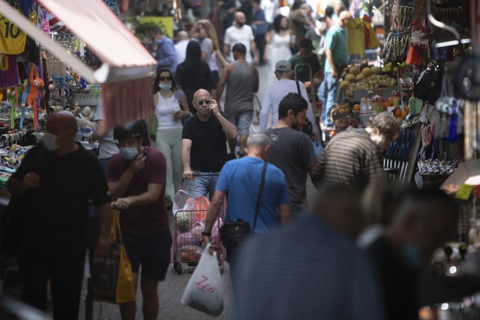 Israelis walk in a market in Tel Aviv, Israel, Sunday, April 18, 2021. Israel has lifted a public mask mandate and fully reopened its education system in the latest easing of coronavirus restrictions following its mass vaccination drive. (AP Photo/Sebastian Scheiner)