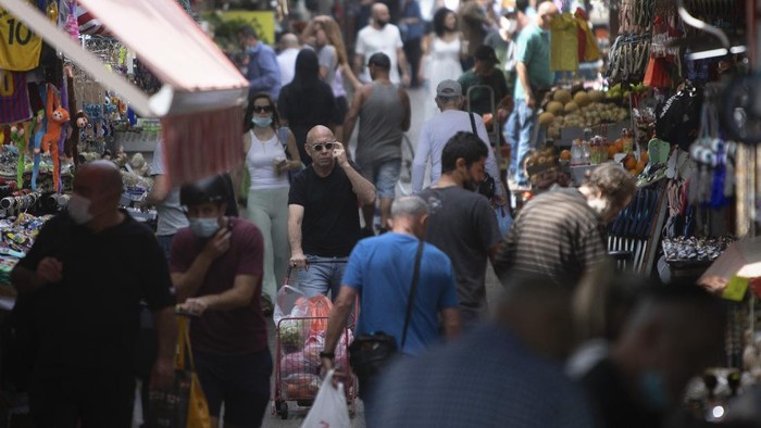 Israelis walk in a market in Tel Aviv, Israel, Sunday, April 18, 2021. Israel has lifted a public mask mandate and fully reopened its education system in the latest easing of coronavirus restrictions following its mass vaccination drive. (AP Photo/Sebastian Scheiner)