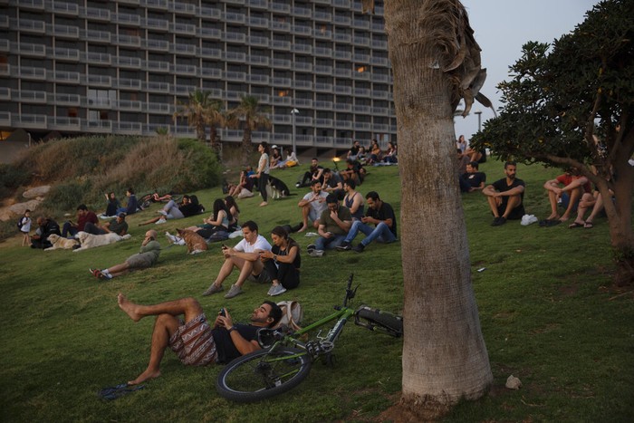 People without face masks watch the sunset, in Tel Aviv, Israel, Sunday, April 18, 2021. Israel has lifted a public mask mandate and fully reopened its education system in the latest easing of coronavirus restrictions following its mass vaccination drive. (AP Photo/Oded Balilty)
