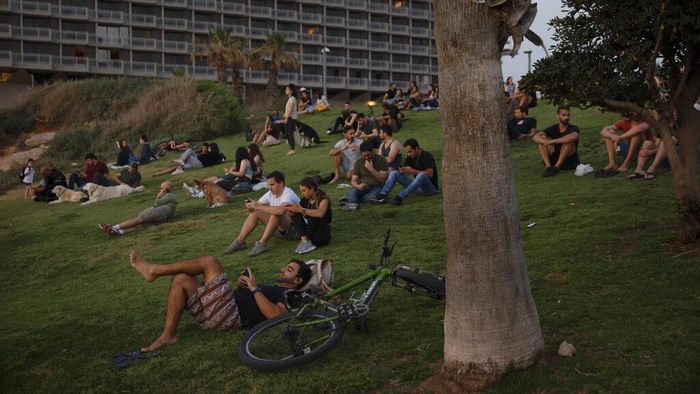 People without face masks watch the sunset, in Tel Aviv, Israel, Sunday, April 18, 2021. Israel has lifted a public mask mandate and fully reopened its education system in the latest easing of coronavirus restrictions following its mass vaccination drive. (AP Photo/Oded Balilty)