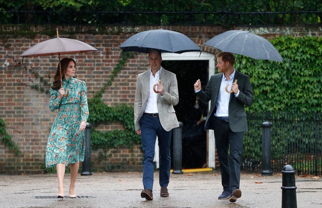 Bahkan saat berjalan di tengah hujan, tiga anggota royal ini masih menyempatkan waktu untuk berbincang. Ini merupakan momen saat mereka mengunjungi The Sunken Garden di Istana Kensington pada 30 Agustus 2017. Foto: Getty Images