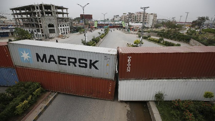 Shipping containers are placed by authorities to block a road leading to the capital as a security measure on the possible anti-France protest march by a banned radical Islamists Tehreek-e-Labaik Pakistan party, in Rawalpindi, Pakistan, Tuesday, April 20, 2021. Pakistan's Parliament is expected to consider a resolution on Tuesday about whether the French envoy should be expelled over the publication of controversial cartoons depicting Islam's Prophet, testing whether the government gives in to threats from radical Islamists. (AP Photo/Anjum Naveed)