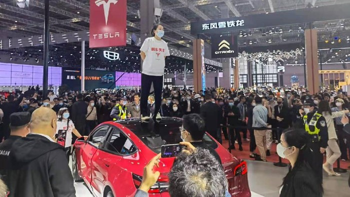 Wanita Ini Demo di Atas Mobil Display Tesla di Pameran, Protes Mobilnya Bermasalah
