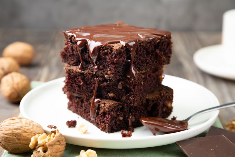 Chocolate spongy brownie cakes with walnuts and melted chocolate topping on a stack