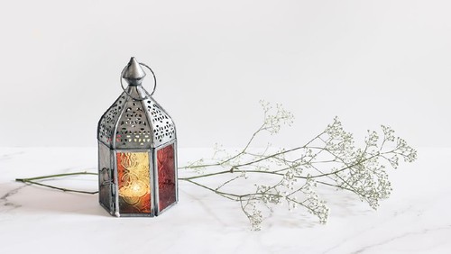 Burning silver vintage Moroccan, Arabic lantern. White gypsophila, babys breath flowers on marble table background, muslim holiday Ramadan Kareem greeting card, invitation. Empty copy space.