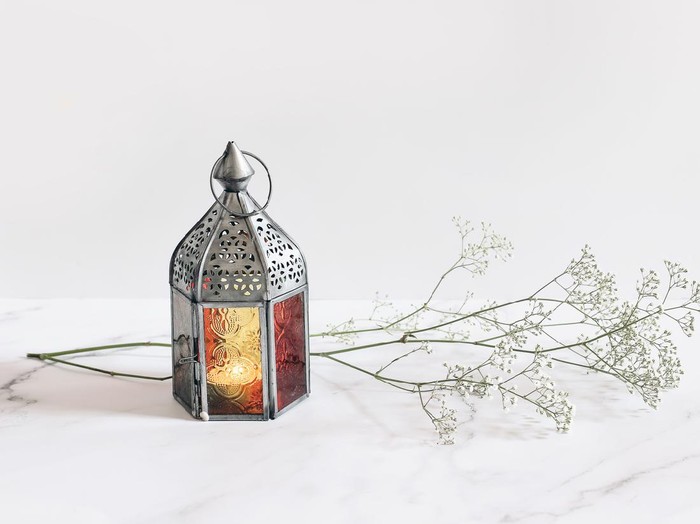 Burning silver vintage Moroccan, Arabic lantern. White gypsophila, babys breath flowers on marble table background, muslim holiday Ramadan Kareem greeting card, invitation. Empty copy space.