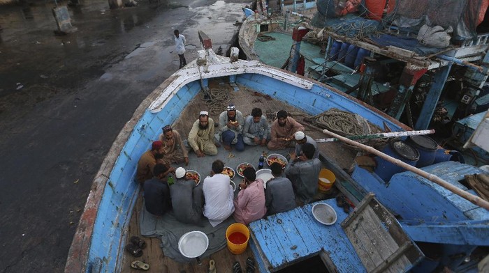 Momen Nelayan Pakistan Buka Puasa di Atas Kapal Fishermen break their fast during the Muslim holy fasting month of Ramadan, on a boat in a dockyard, in Karachi, Pakistan, Tuesday, April 20, 2021. (AP Photo/Fareed Khan)