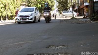 Ada jalan berlubang, tambalan aspal yang merekah kembali, kontur jalan bergelombang dan ada lubang jalan yang diurug menggunakan batu krikil dan tanah.