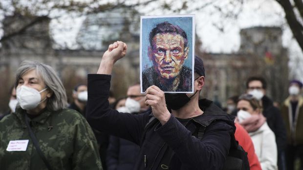 A man holds a poster with a drawing of Russian opposition leader Alexei Navalny, as he protests against the jailing of the Russian opposition leader near the chancellery in Berlin, Germany, Wednesday, April 21, 2021. In the background the Reichstag building with the German parliament. (AP Photo/Markus Schreiber)