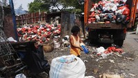 Pemulung memilah sampah yang masih bisa dijual seperti botol plastik dan kardus.