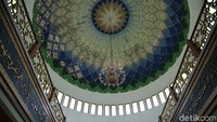 Bagian dalam kubah masjid dihiasi goresan-goresan geometris saling melintang dengan warna dominan hijau dan emas yang melingkari gambar bintang sebagai ciri khas seni Islam.