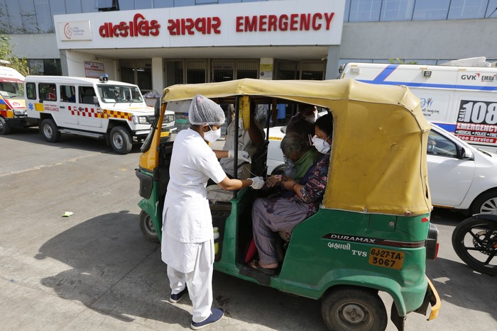 A COVID-19 patient attended inside a vehicle at a dedicated COVID-19 government hospital in Ahmedabad, India, Thursday, April 22, 2021. A fire killed 13 COVID-19 patients in a hospital in western India early Friday as an extreme surge in coronavirus infections leaves the nation short of medical care and oxygen. India reported another global record in daily infections for a second straight day Friday, adding 332,730 new cases. The surge already has driven its fragile health systems to the breaking point with understaffed hospitals overflowing with patients and critically short of supplies. (AP Photo/Ajit Solanki)