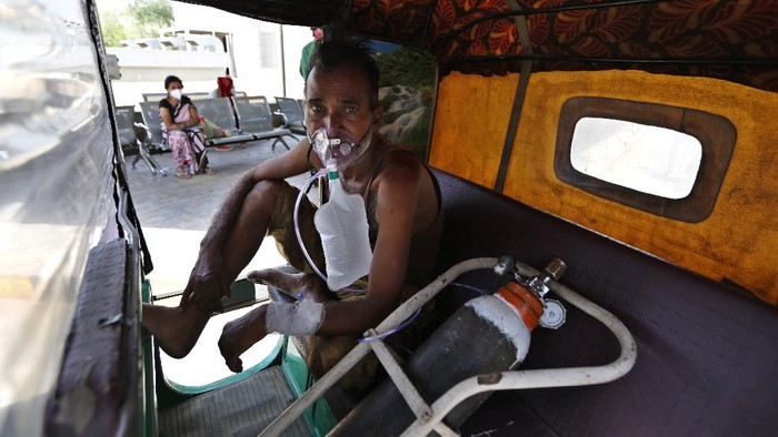 A COVID-19 patient attended inside a vehicle at a dedicated COVID-19 government hospital in Ahmedabad, India, Thursday, April 22, 2021. A fire killed 13 COVID-19 patients in a hospital in western India early Friday as an extreme surge in coronavirus infections leaves the nation short of medical care and oxygen. India reported another global record in daily infections for a second straight day Friday, adding 332,730 new cases. The surge already has driven its fragile health systems to the breaking point with understaffed hospitals overflowing with patients and critically short of supplies. (AP Photo/Ajit Solanki)