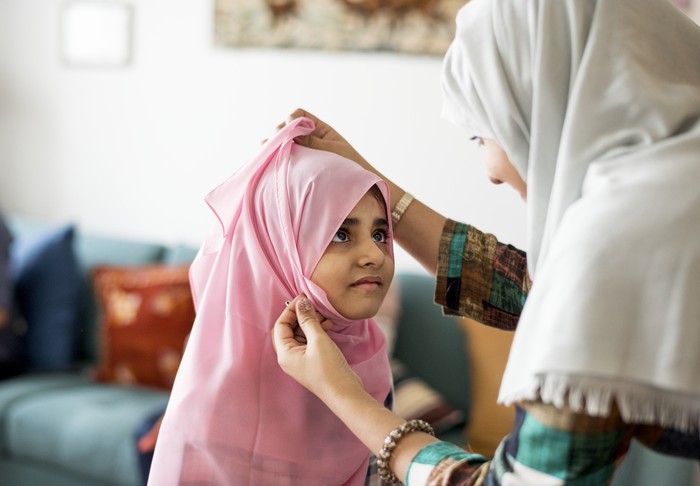 Muslim mom teaching daughter how to wear a Hijab