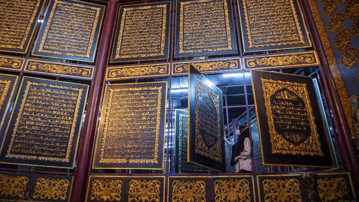 Pengunjung membaca ayat-ayat yang ada di Al Quran Al-Akbar di Palembang, Sumatera Selatan, Jumat (23/4/2021). Keberadaan Al Quran raksasa yang diukir di atas kayu trembesi itu menjadi destinasi wisata religi di Kota Palembang selama bulan Ramadhan. ANTARA FOTO/Nova Wahyudi/wsj.