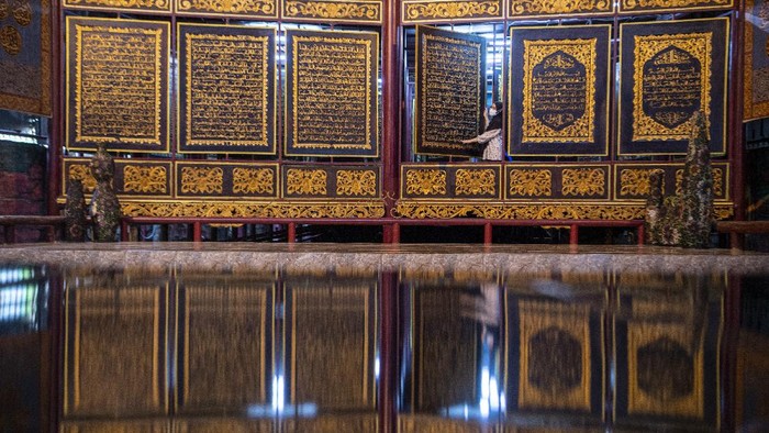 Pengunjung membaca ayat-ayat yang ada di Al Quran Al-Akbar di Palembang, Sumatera Selatan, Jumat (23/4/2021). Keberadaan Al Quran raksasa yang diukir di atas kayu trembesi itu menjadi destinasi wisata religi di Kota Palembang selama bulan Ramadhan. ANTARA FOTO/Nova Wahyudi/wsj.
