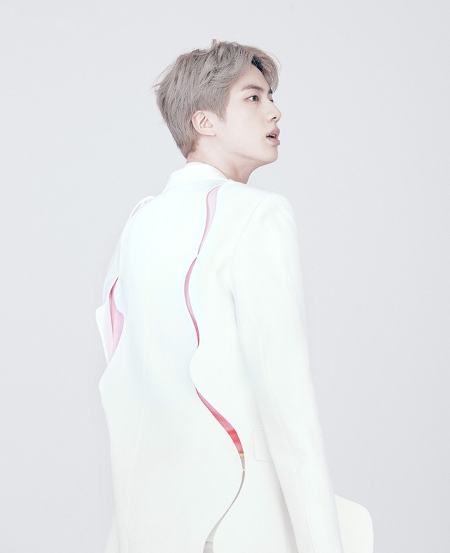 Jin si Worldwide Handsome mengenakan jas putih berdetail cut-out yang dipadu celana warna senada dan kaus pink pastel. Foto: Instagram/@louisvuitton
