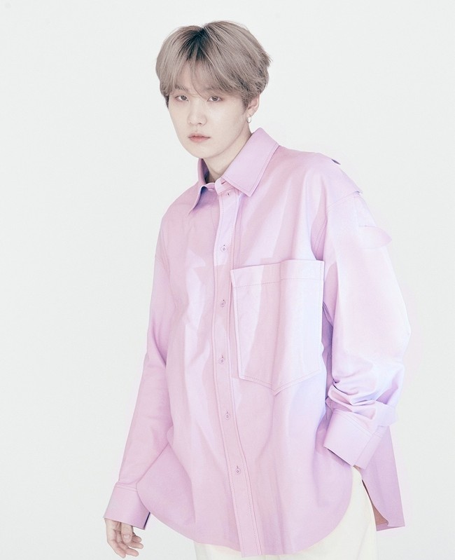 Rapper Suga tampil simpel berbalut kemeja oversized warna pink. Ia memadukan kemejanya dengan celana putih dan sneakers. Foto: Instagram/@louisvuitton