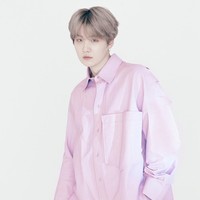 Rapper Suga tampil simpel berbalut kemeja oversized warna pink. Ia memadukan kemejanya dengan celana putih dan sneakers. Foto: Instagram/@louisvuitton