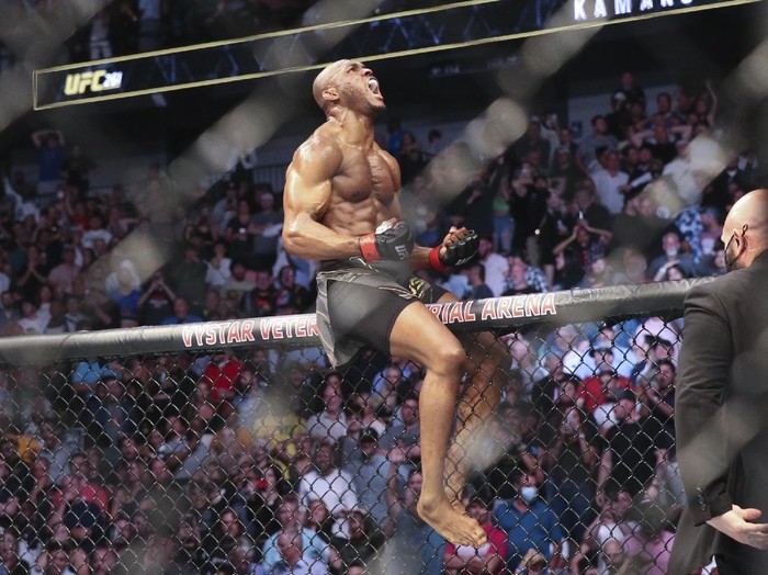 Kamaru Usman celebrates his win atop the octagon fence after a UFC 261 mixed martial arts bout against Jorge Masvidal early Sunday, April 25, 2021, in Jacksonville, Fla. (AP Photo/Gary McCullough)