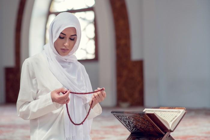 Young beautiful Muslim Woman Praying In Mosque.