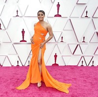 Ariana DeBose memilih gaun oranye dengan rok belahan tinggi yang mengekspos kaki jenjangnya. (Foto: AP/Chris Pizzello)