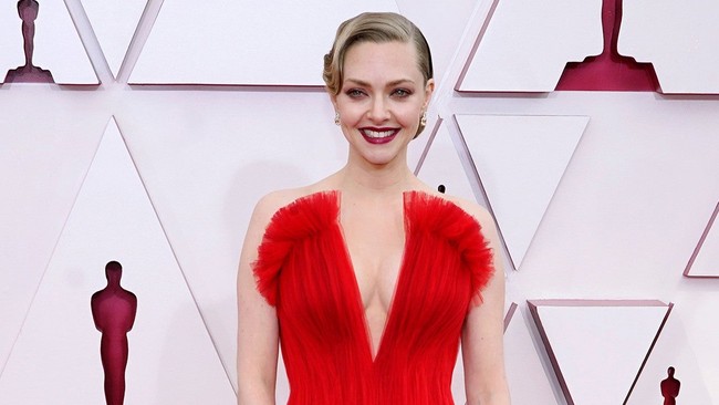 Amand Seyfried mencuri perhatian dengan gaun merahnya. Makeup dan rambutnya pun mendukung penampilan secara keseluruhan. Amanda tampil dengan makeup flawless dengan pulasan lipstik merah. Rambutnya ditata cepol ala tahun 20-an. Foto: dok. Getty Images