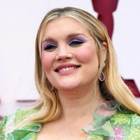 Aktris Emerald Fennel tampil ceria dan semarak dengan gaun bermotif floral. Tampilannya semakin fun dengan eyeshadow ungu. Foto: dok. Getty Images