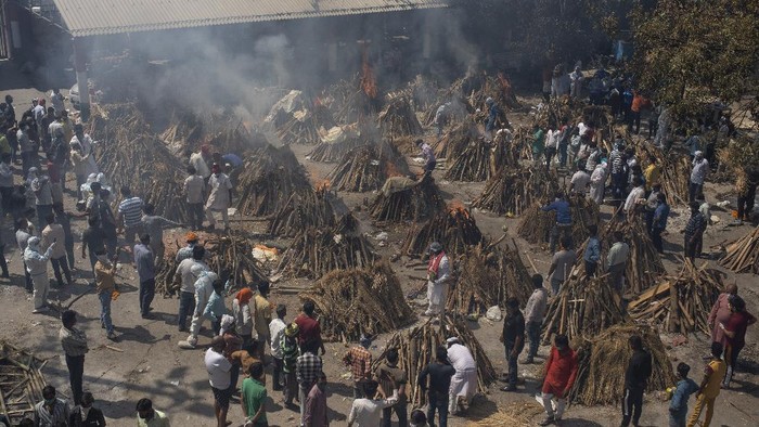 Makin Ganas! Kremasi Massal Gegara Tsunami Corona di India People perform rituals next to a funeral pyre for a family member who died of COVID-19 at a ground that has been converted into a crematorium for mass cremation of COVID-19 victims in New Delhi, India, Saturday, April 24, 2021. Delhi has been cremating so many bodies of coronavirus victims that authorities are getting requests to start cutting down trees in city parks, as a second record surge has brought India's tattered healthcare system to its knees. (AP Photo/Altaf Qadri)