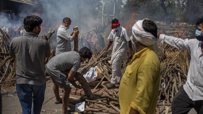 Makin Ganas! Kremasi Massal Gegara Tsunami Corona di India People perform rituals next to a funeral pyre for a family member who died of COVID-19 at a ground that has been converted into a crematorium for mass cremation of COVID-19 victims in New Delhi, India, Saturday, April 24, 2021. Delhi has been cremating so many bodies of coronavirus victims that authorities are getting requests to start cutting down trees in city parks, as a second record surge has brought India's tattered healthcare system to its knees. (AP Photo/Altaf Qadri)