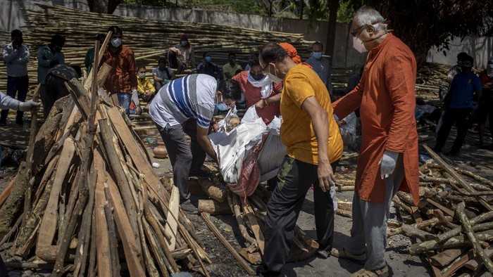 People perform rituals next to a funeral pyre for a family member who died of COVID-19 at a ground that has been converted into a crematorium for mass cremation of COVID-19 victims in New Delhi, India, Saturday, April 24, 2021. Delhi has been cremating so many bodies of coronavirus victims that authorities are getting requests to start cutting down trees in city parks, as a second record surge has brought Indias tattered healthcare system to its knees. (AP Photo/Altaf Qadri)