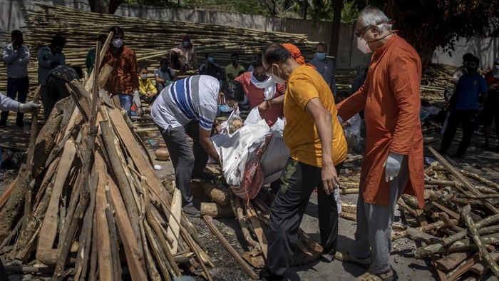 Makin Ganas! Kremasi Massal Gegara Tsunami Corona di India People perform rituals next to a funeral pyre for a family member who died of COVID-19 at a ground that has been converted into a crematorium for mass cremation of COVID-19 victims in New Delhi, India, Saturday, April 24, 2021. Delhi has been cremating so many bodies of coronavirus victims that authorities are getting requests to start cutting down trees in city parks, as a second record surge has brought India's tattered healthcare system to its knees. (AP Photo/Altaf Qadri)