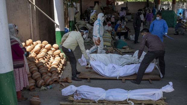 People perform rituals next to a funeral pyre for a family member who died of COVID-19 at a ground that has been converted into a crematorium for mass cremation of COVID-19 victims in New Delhi, India, Saturday, April 24, 2021. Delhi has been cremating so many bodies of coronavirus victims that authorities are getting requests to start cutting down trees in city parks, as a second record surge has brought India's tattered healthcare system to its knees. (AP Photo/Altaf Qadri)
