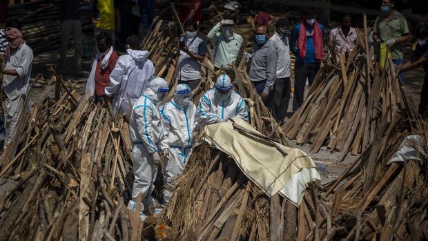 People perform rituals next to a funeral pyre for a family member who died of COVID-19 at a ground that has been converted into a crematorium for mass cremation of COVID-19 victims in New Delhi, India, Saturday, April 24, 2021. Delhi has been cremating so many bodies of coronavirus victims that authorities are getting requests to start cutting down trees in city parks, as a second record surge has brought India's tattered healthcare system to its knees. (AP Photo/Altaf Qadri)