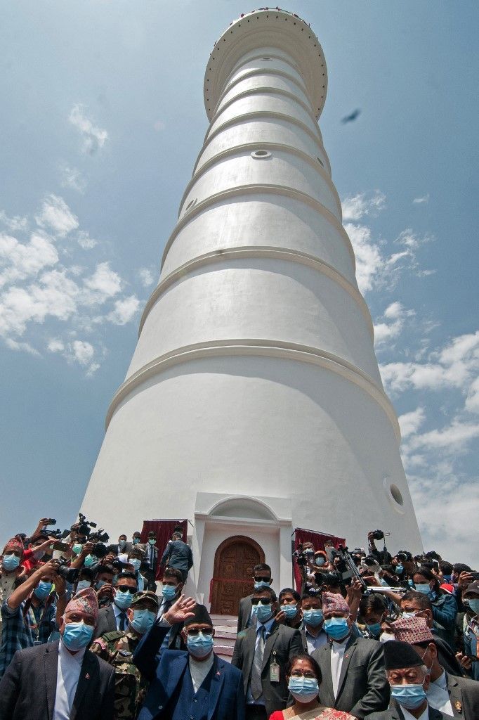The new 23-storey, 84-metre (276-foot) white tower, built next to the rubble of the 19th-century historic Dharahara tower that collapsed in a devastating 2015 earthquake, is pictured during its inauguration ceremony in Kathmandu on April 24, 2021. (Photo by Bikash KARKI / AFP)