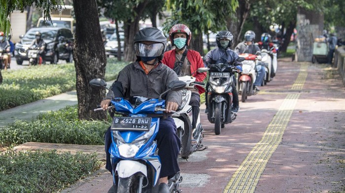 PENGENDARA MOTOR GUNAKAN TROTOAR DI DAAN MOGOT Pengendara sepeda motor melintas di atas trotoar kawasan Daan Mogot, Jakarta Barat, Senin (26/4/2021). Tindakan pengendara sepeda motor yang menggunakan trotoar untuk menghindari kepadatan lalu lintas tersebut melanggar hak pejalan kaki dan penyandang disabilitas serta dapat dikenai hukuman sesuai pasal 284 dengan ancaman denda Rp500 ribu. ANTARA FOTO/M Risyal Hidayat/rwa.