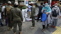 Sejumlah anggota Satpol PP memperingatkan PKL yang berjualan di trotoar untuk pindah tempat.