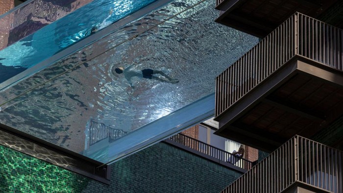 Serunya Mencoba Kolam Renang Gantung Pertama di Dunia LONDON, ENGLAND - APRIL 23: A swimmer takes part in a photoshoot to advertise the new 'sky pool' near Embassy Gardens in south-west London on April 23, 2021 in London, England. The pool sits 10 storeys up, spanning 25 metres between two apartment buildings and will open to residents from May 19, 2021. (Photo by Dan Kitwood/Getty Images)