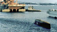 Kapal selam itu diangkat dengan kabel baja yang diturunkan dari tongkang sebelum dijepit di bawah tongkang. Menara conning Kursk yang menonjol dan sirip ekor dipasang erat di relung yang ada di tongkang. Proses evakuasi kapal Kursk ini menjadi momen bersejarah. Pasalnya, kapal yang diangkat ialah kapal dengan berat 17 ribu ton. AFP PHOTO/POOL/STRINGER/File.